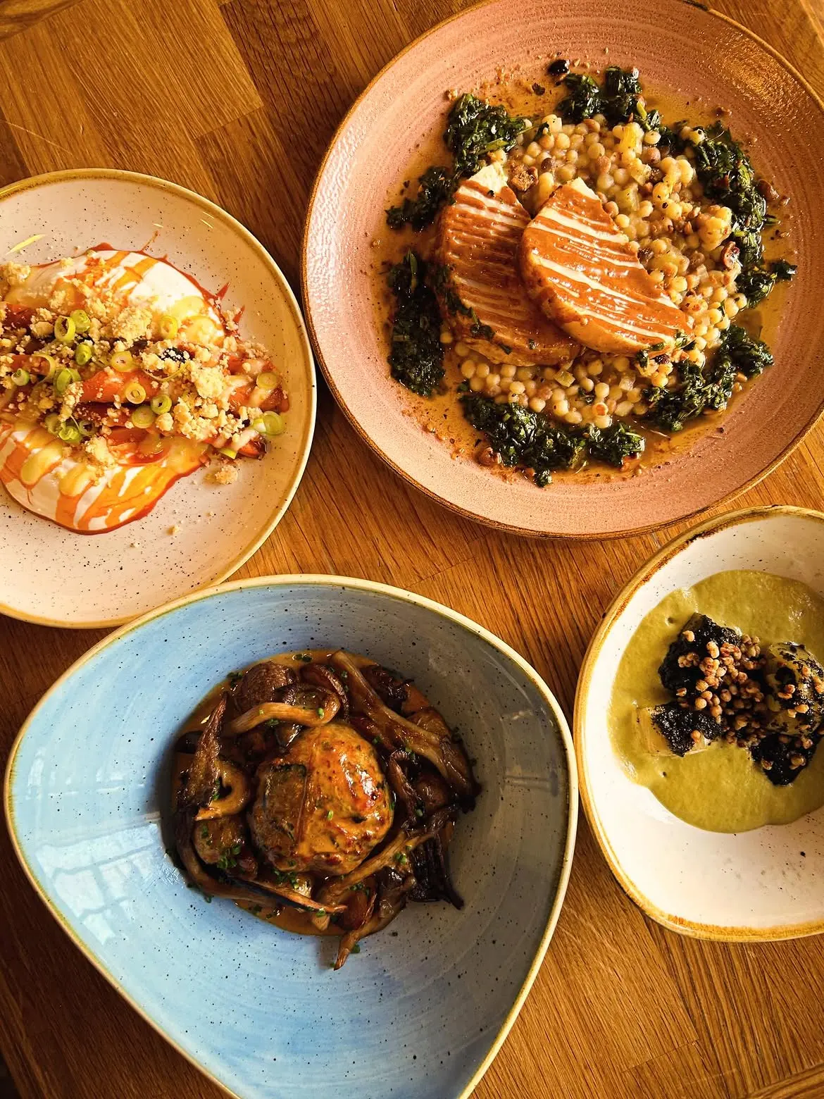 Quatre assiettes du menu du midi, vues de dessus, sur une table en bois